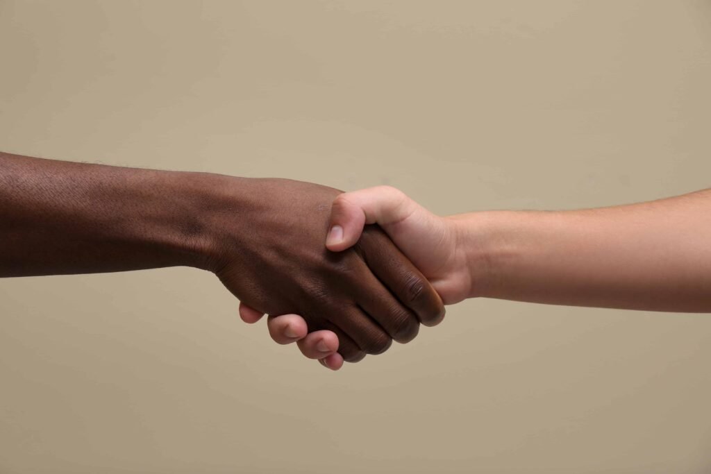 two people shaking hands with tan background 